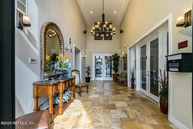 8539 Gate Pkwy W Unit 1723, Jacksonville, FL 32216 - hallway featuring stone tile floors, baseboards, an inviting chandelier, vaulted ceiling, and french doors