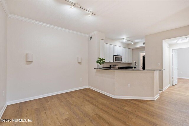 8539 Gate Pkwy W Unit 1723, Jacksonville, FL 32216 - kitchen featuring dark countertops, baseboards, stainless steel appliances, light wood-style floors, and white cabinetry