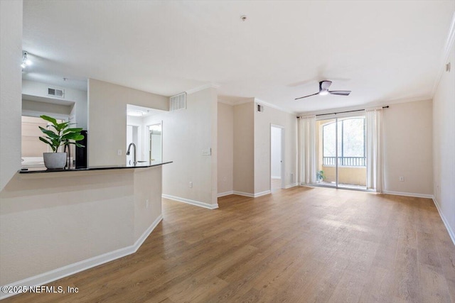 8539 Gate Pkwy W Unit 1723, Jacksonville, FL 32216 - unfurnished living room with visible vents, baseboards, ornamental molding, wood finished floors, and a ceiling fan