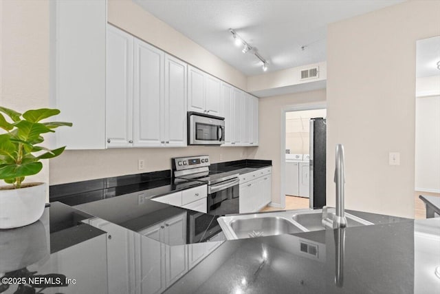 8539 Gate Pkwy W Unit 1723, Jacksonville, FL 32216 - kitchen with dark countertops, visible vents, washer and clothes dryer, appliances with stainless steel finishes, and white cabinetry