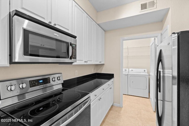8539 Gate Pkwy W Unit 1723, Jacksonville, FL 32216 - kitchen featuring dark countertops, visible vents, appliances with stainless steel finishes, white cabinetry, and separate washer and dryer
