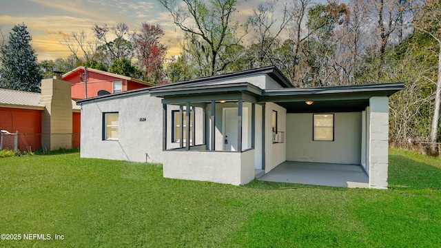 back of house featuring a yard, fence, and stucco siding