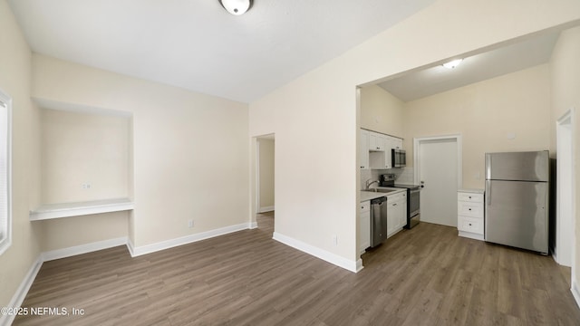 kitchen with white cabinetry, stainless steel appliances, light countertops, and wood finished floors