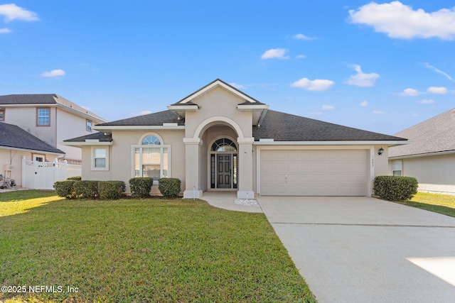 view of front of property with stucco siding, concrete driveway, a front yard, and fence