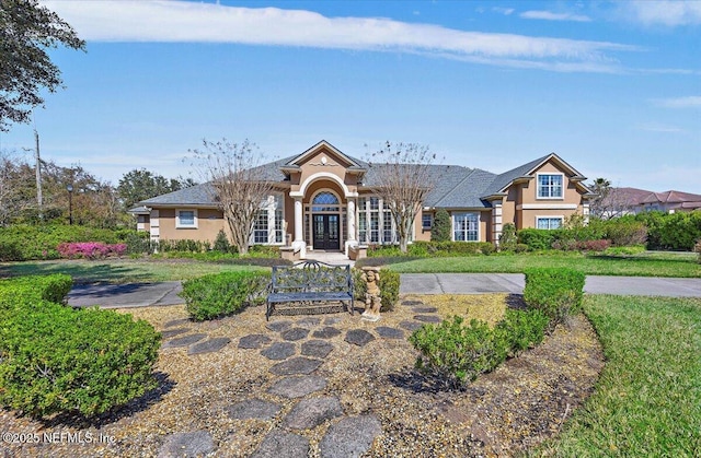 view of front of house featuring a front lawn, french doors, and stucco siding