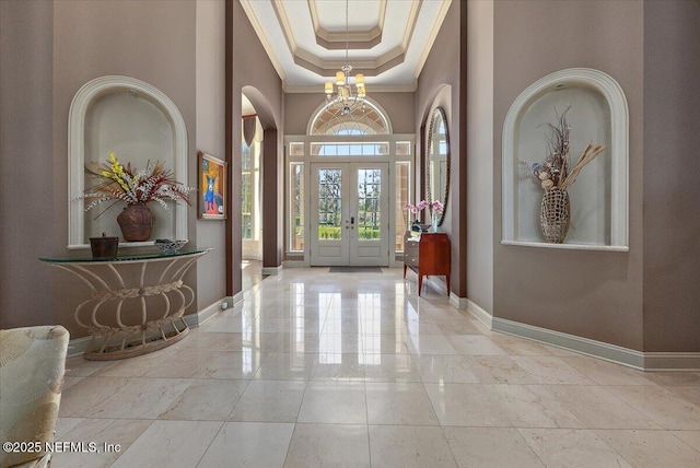 entryway featuring an inviting chandelier, crown molding, baseboards, and a tray ceiling