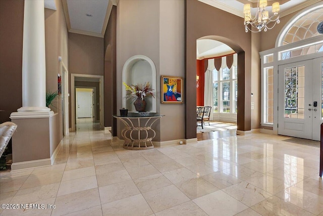 entrance foyer featuring baseboards, arched walkways, ornamental molding, and a towering ceiling