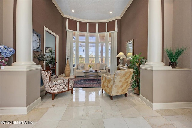 living area featuring crown molding, decorative columns, baseboards, and light tile patterned floors