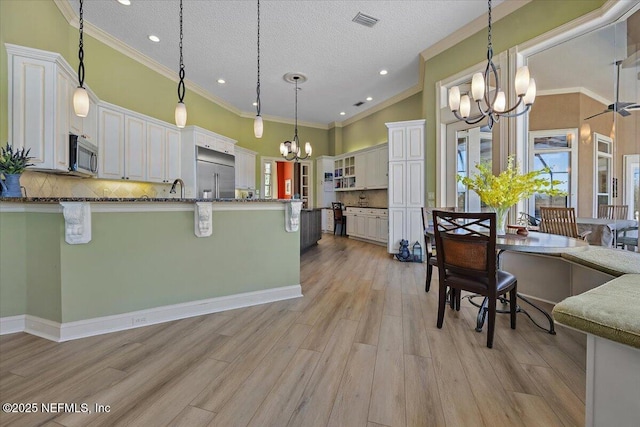 kitchen featuring visible vents, appliances with stainless steel finishes, a kitchen bar, light wood-type flooring, and a chandelier