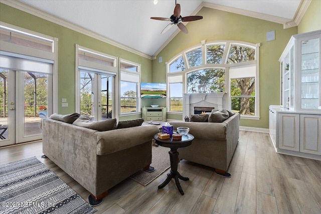 living room with light wood finished floors, ceiling fan, ornamental molding, french doors, and high vaulted ceiling