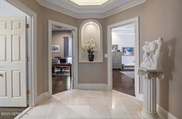 hallway with light tile patterned floors, baseboards, and crown molding