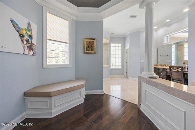 hall featuring dark wood finished floors, crown molding, baseboards, and ornate columns