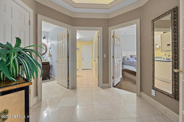 corridor with light tile patterned floors, baseboards, and ornamental molding