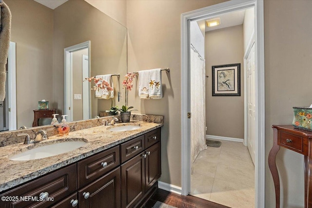 bathroom with double vanity, baseboards, and a sink