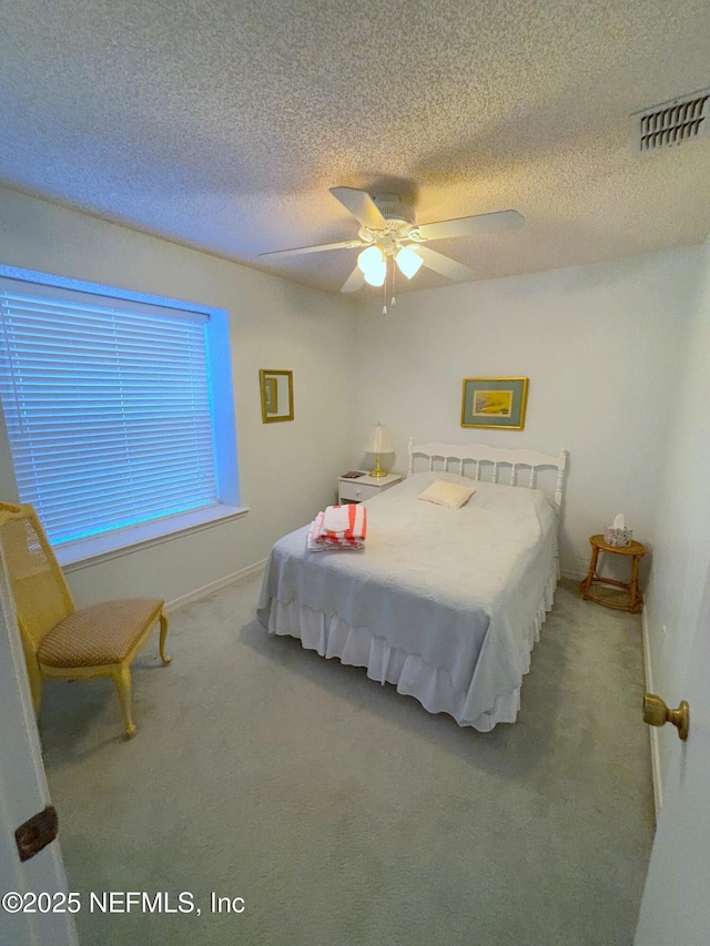 carpeted bedroom with ceiling fan, a textured ceiling, visible vents, and baseboards