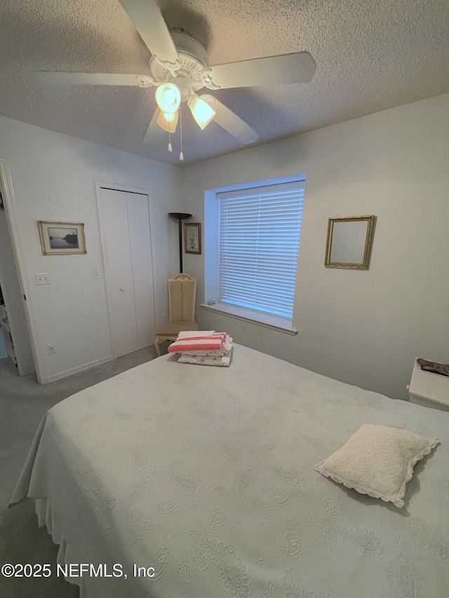 carpeted bedroom featuring a textured ceiling, ceiling fan, and a closet