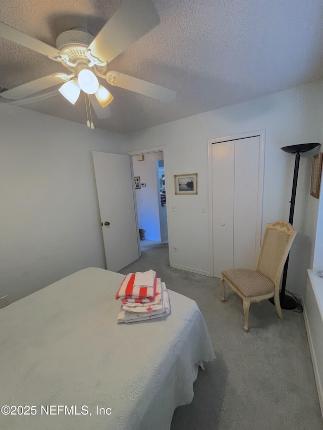 bedroom with a ceiling fan, carpet, a closet, and a textured ceiling