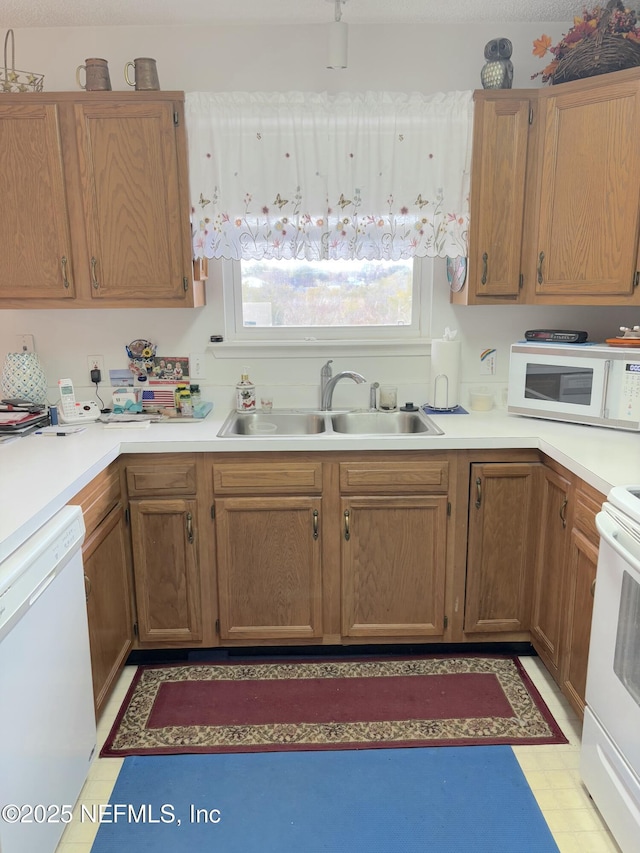 kitchen featuring white appliances, light countertops, a sink, and light floors