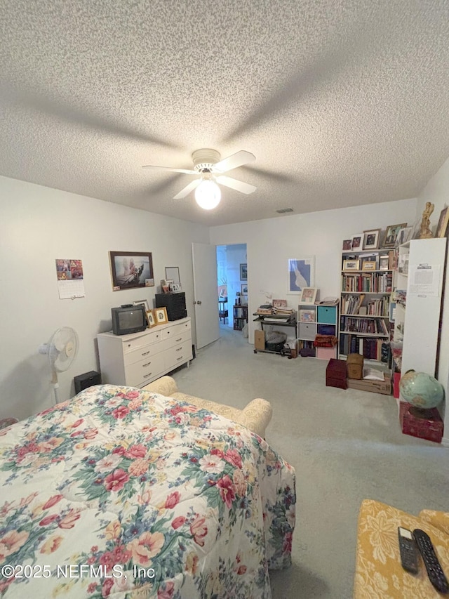 bedroom with a ceiling fan, light carpet, and a textured ceiling