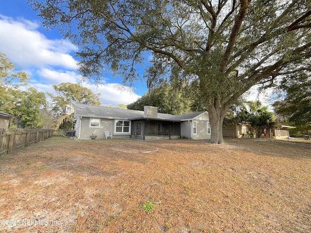 back of house featuring a chimney, cooling unit, fence, and a sunroom