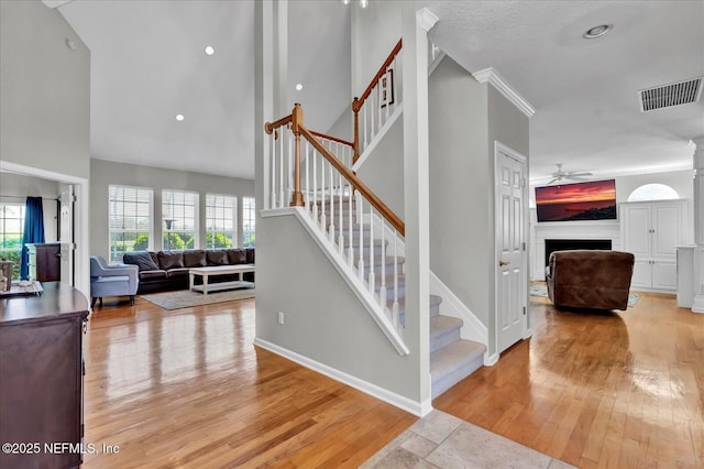 staircase with baseboards, wood finished floors, visible vents, and ceiling fan