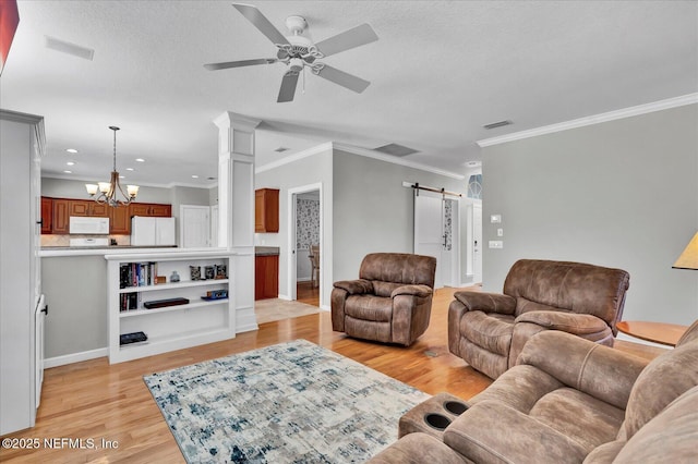 living area featuring light wood-style flooring, a textured ceiling, ceiling fan with notable chandelier, and a barn door