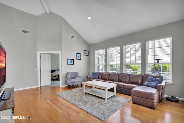 living room with beam ceiling, visible vents, baseboards, and wood finished floors