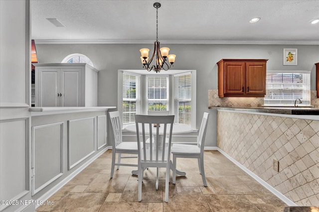 dining room with a textured ceiling, baseboards, crown molding, and an inviting chandelier