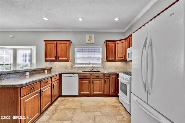 kitchen with a sink, dark countertops, white appliances, a peninsula, and brown cabinetry