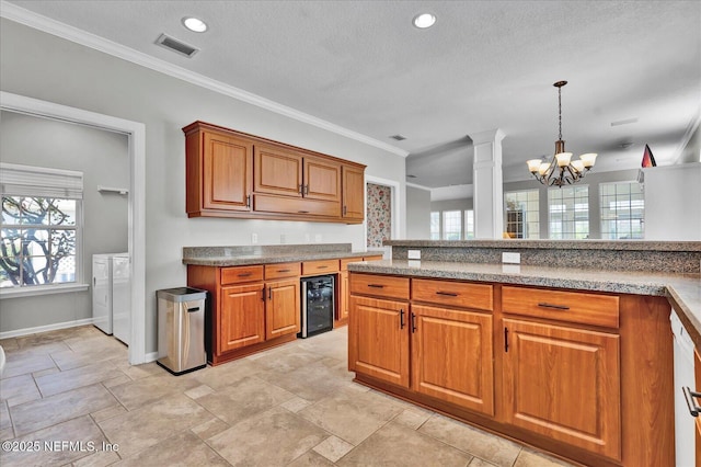 kitchen with visible vents, independent washer and dryer, wine cooler, brown cabinetry, and hanging light fixtures