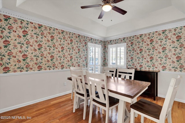 dining area with light wood-type flooring, a wainscoted wall, and wallpapered walls