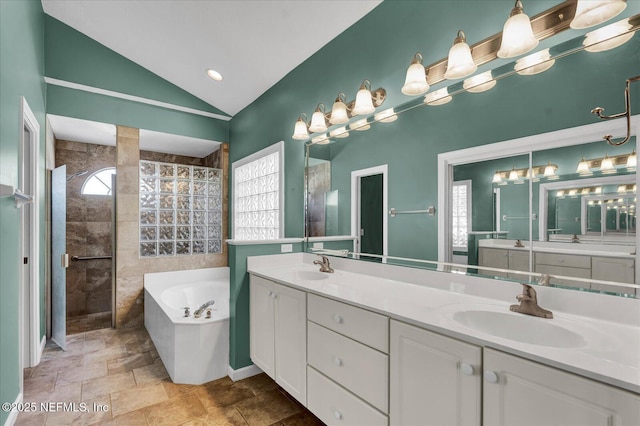 full bath with a sink, a garden tub, double vanity, and vaulted ceiling