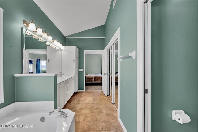 full bath with vanity, lofted ceiling, a garden tub, and ensuite bathroom