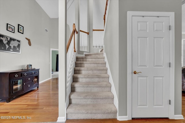 staircase featuring visible vents, baseboards, and wood finished floors