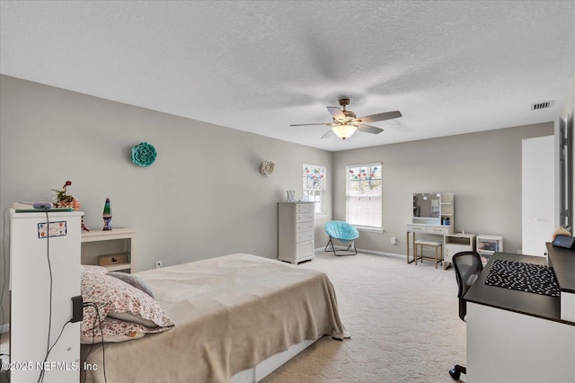 carpeted bedroom featuring ceiling fan, baseboards, visible vents, and a textured ceiling