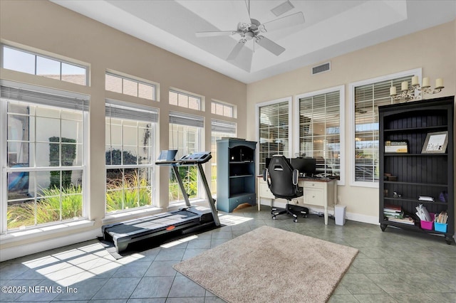 tiled office space featuring visible vents, baseboards, a tray ceiling, and a ceiling fan