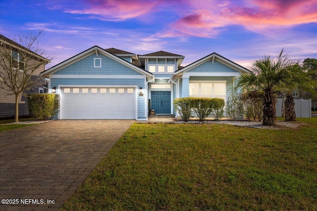 view of front of property featuring a garage, decorative driveway, and a front lawn