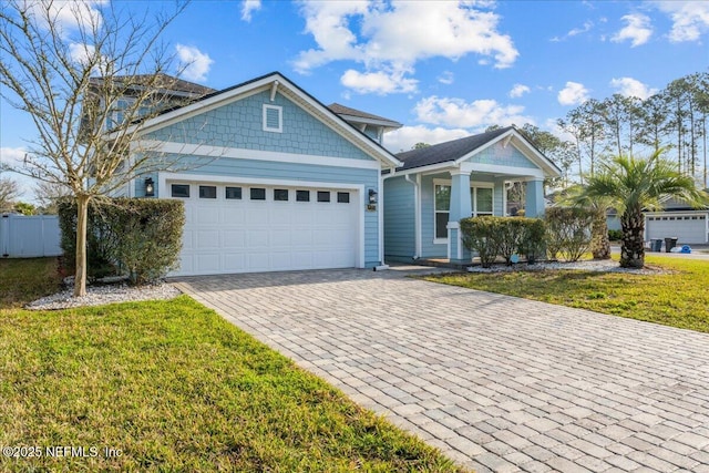 view of front of property with an attached garage, fence, decorative driveway, and a front yard