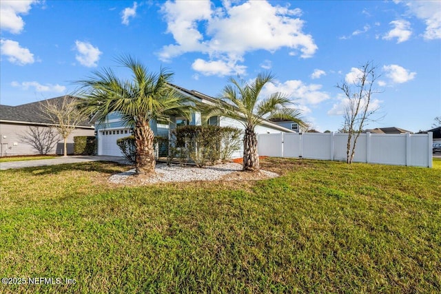 view of yard featuring driveway, an attached garage, and fence