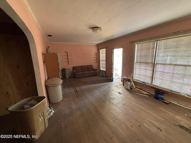 living area with arched walkways, wood finished floors, visible vents, and crown molding