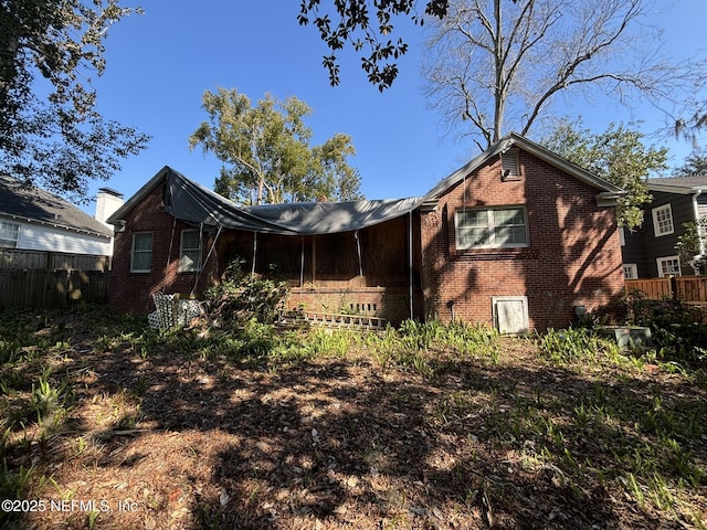 back of house with brick siding and fence