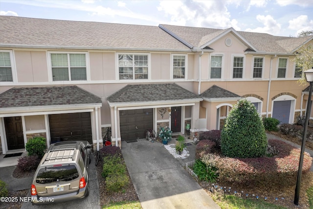 multi unit property with a shingled roof, driveway, an attached garage, and stucco siding