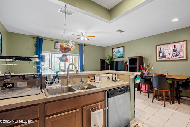 kitchen featuring light tile patterned floors, visible vents, brown cabinetry, stainless steel dishwasher, and a sink