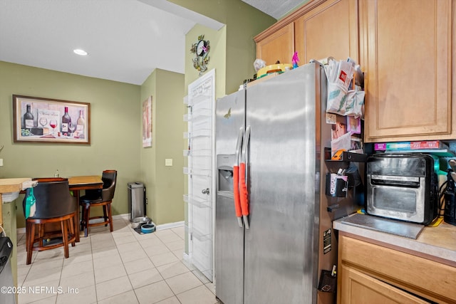 kitchen featuring light tile patterned flooring, recessed lighting, baseboards, light countertops, and stainless steel fridge with ice dispenser