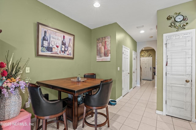 dining area featuring arched walkways, light tile patterned floors, recessed lighting, and baseboards