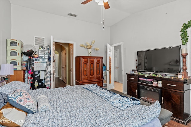 bedroom featuring ceiling fan, arched walkways, wood finished floors, visible vents, and vaulted ceiling