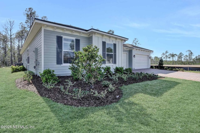 view of side of home with driveway, central AC, a garage, a lawn, and board and batten siding