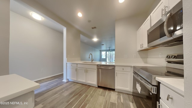 kitchen featuring stainless steel appliances, visible vents, light wood-style flooring, white cabinetry, and a sink