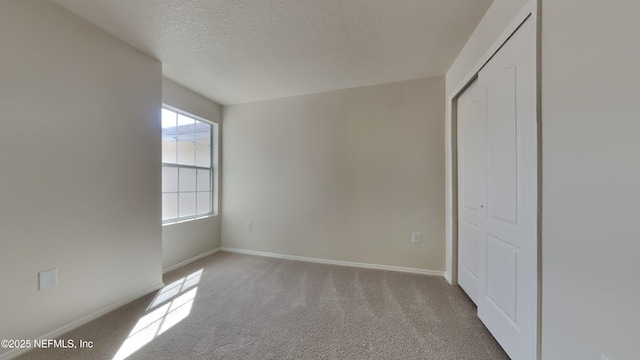 unfurnished bedroom featuring a closet, carpet flooring, a textured ceiling, and baseboards