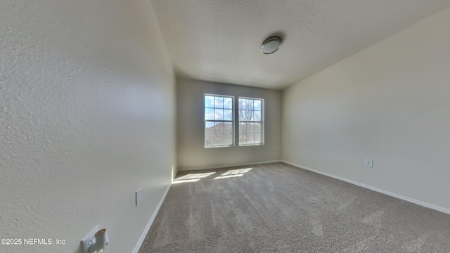 carpeted empty room with baseboards and a textured ceiling